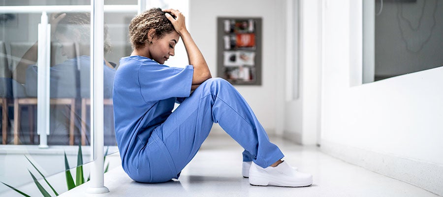 nurse sitting on floor with head in hands